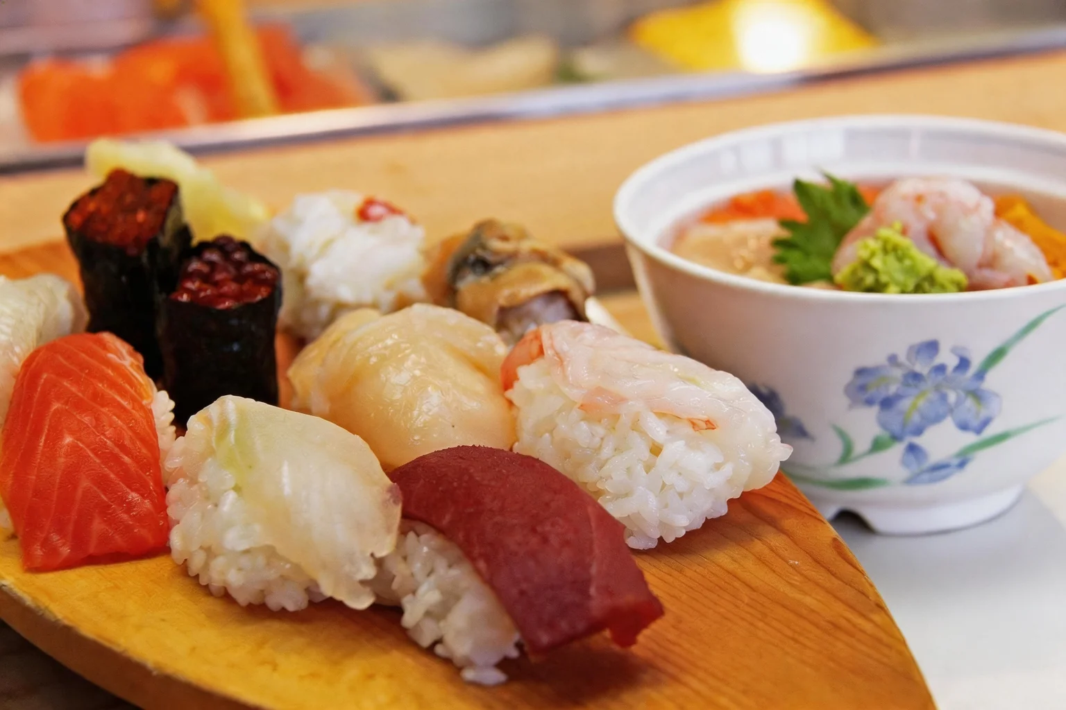 Sushis sur planche en bois, bol blanc à motif d'iris.